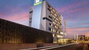 A Holiday Inn hotel with a modern design, featuring a prominent vertical sign and multiple floors. - Holiday Inn BERN-WESTSIDE by IHG (Bern)