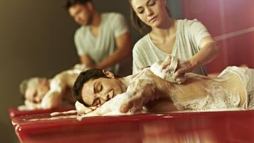 Une séance de massage sur une table de massage rouge, où une personne reçoit un massage du dos.