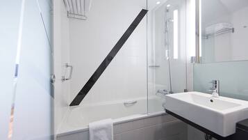 Un baño moderno con cabina de ducha de vidrio, una bañera blanca y un lavamanos con encimera negra.
