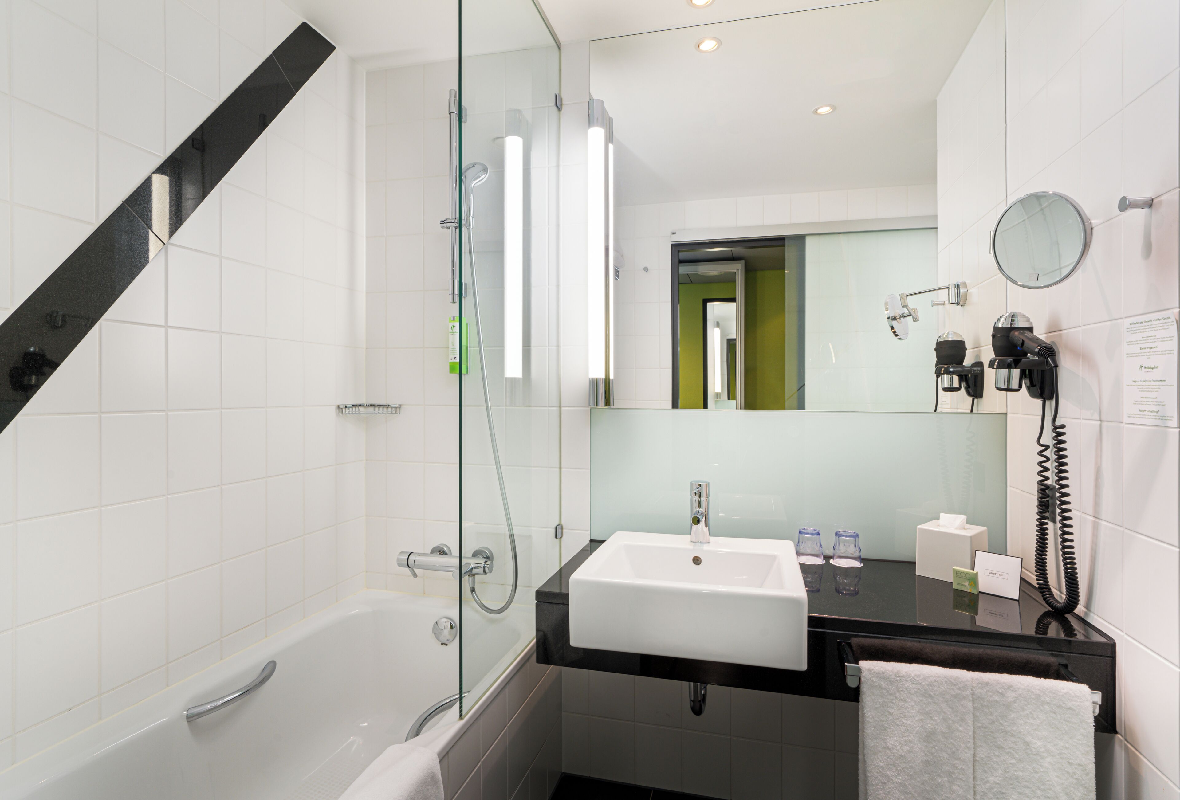 A modern bathroom with a glass-enclosed shower, a white sink, and a black countertop.