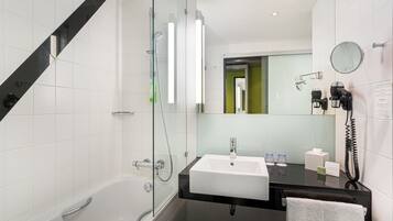 A modern bathroom with a glass-enclosed shower, a white sink, and a black countertop.