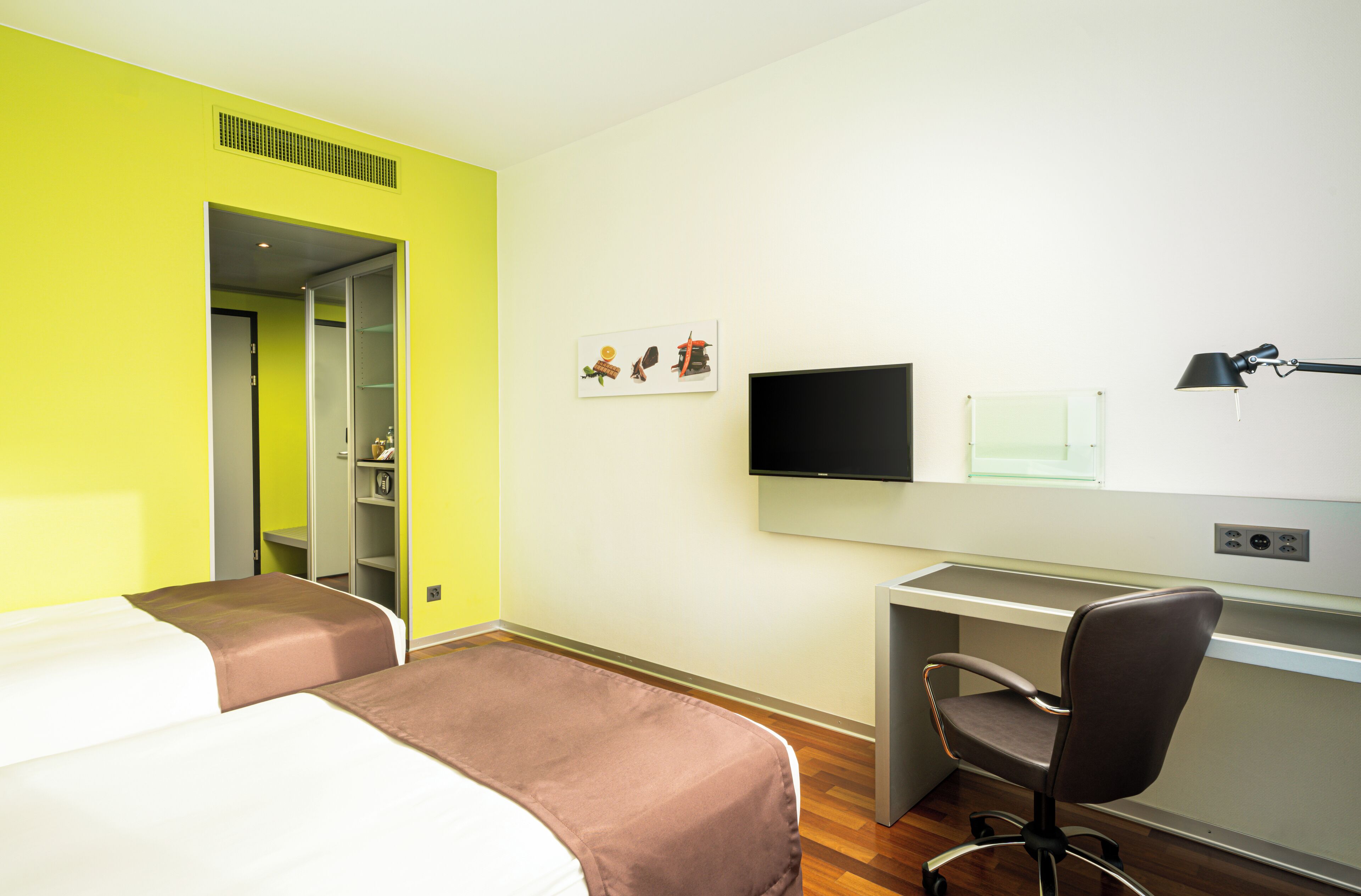 Una habitación de hotel con dos camas, un escritorio, una silla, un televisor y una ventana.