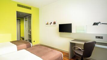 Una habitación de hotel con dos camas, un escritorio, una silla, un televisor y una ventana.