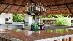 A bar area with a variety of liquor bottles and a shelf with more bottles. - The Yellow Bird (Negril)