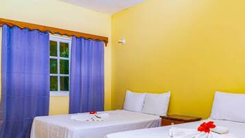 Une chambre d’hôtel avec deux lits, une fenêtre avec des rideaux bleus et un mur jaune.