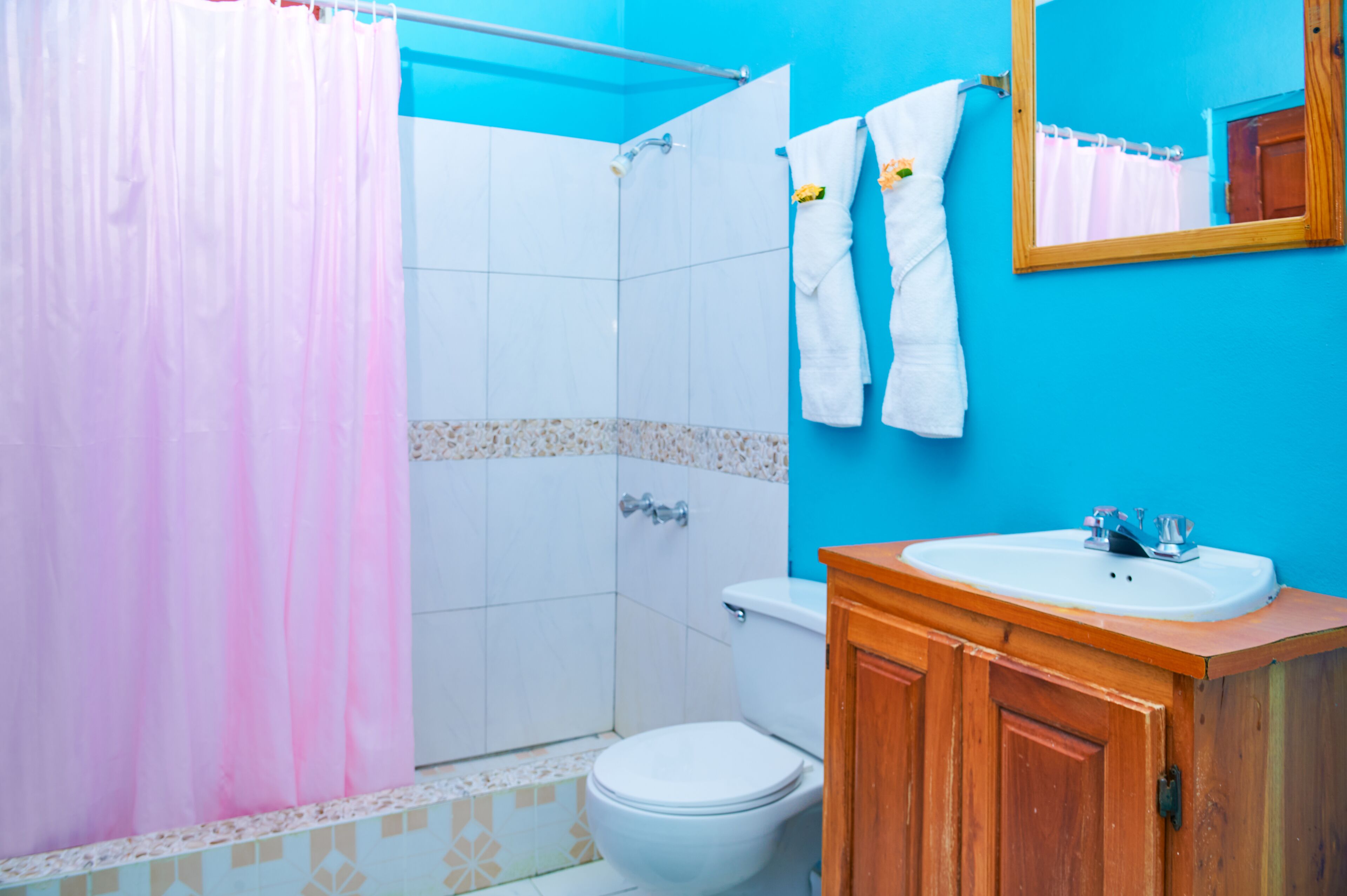 A bathroom with a shower, toilet, sink, and wooden cabinets.