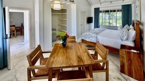 A bedroom with a bed, bedside table, and a view of the outdoors. - The Yellow Bird (Negril)