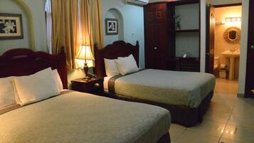 Two single beds with matching headboards and pillows, a nightstand with a lamp, and a small table with a chair.