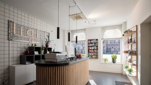 Moderni vastaanottotiski, jossa on puuviimeistely, neonvalokyltti, jossa lukee sana ”Light”, ja suuret ikkunat, joista avautuu näkymä kaupunkiin.