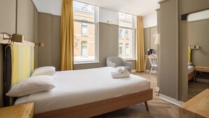 Hotellihuone, jossa on suuri sänky, työpöytä, tuoli ja peili.