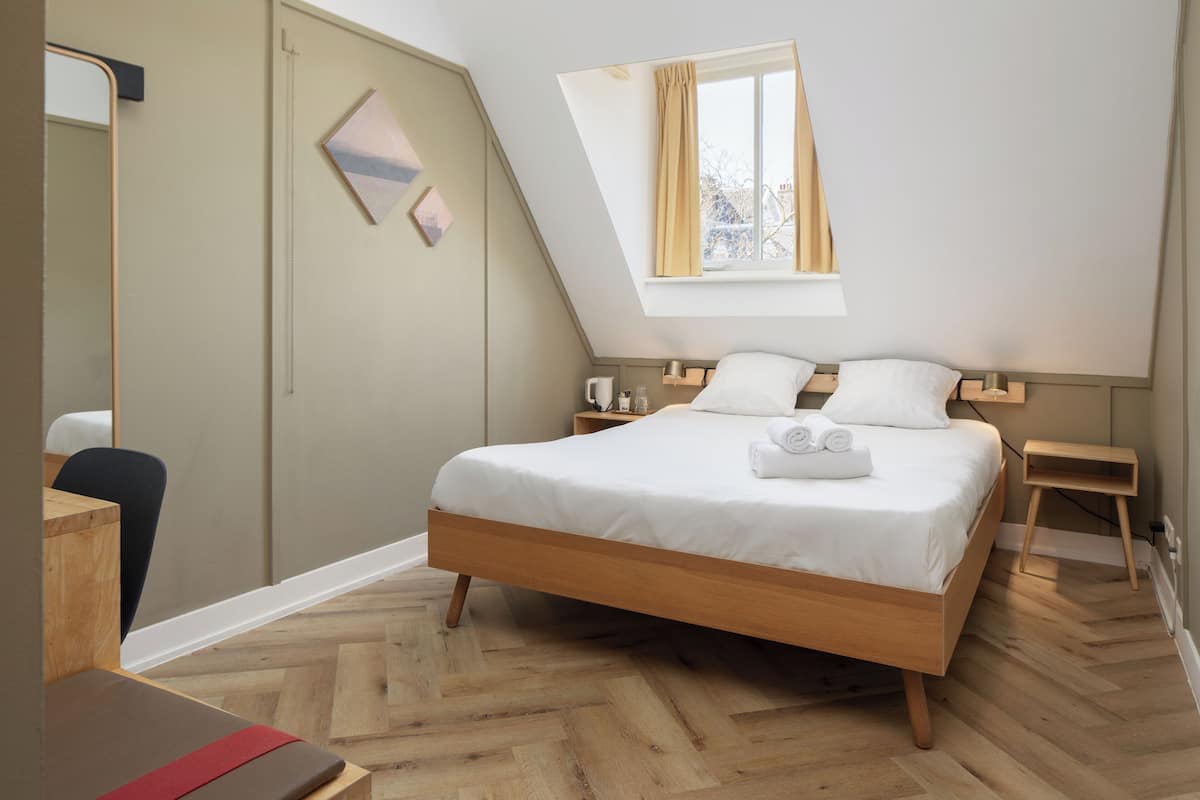 A modern bedroom with a wooden bed, a desk, and a small table.