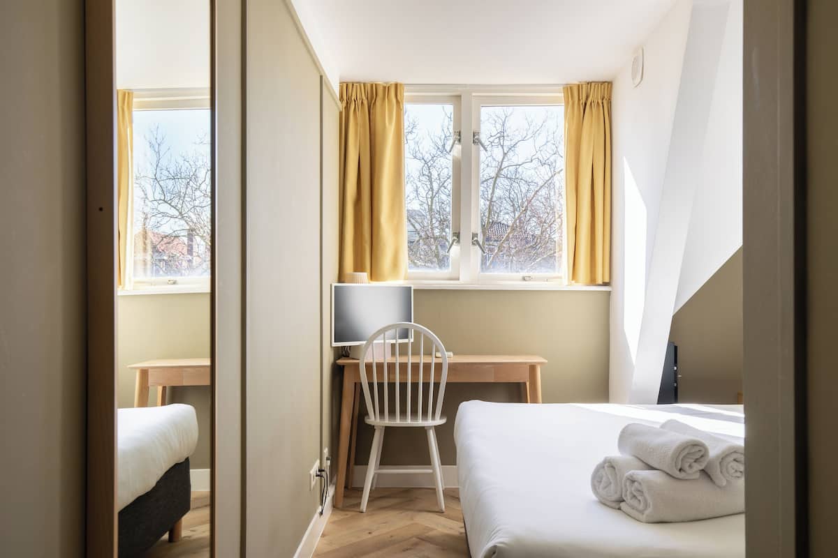 A bedroom with a bed, a desk, and a chair.