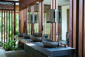 A long, narrow bathroom with a central sink area featuring multiple stone basins and modern faucets. - Pachira Lodge (Colorado)