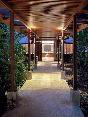 A covered walkway with a wooden ceiling and concrete pillars, leading to a building with a sign that reads 'Pachira Lodge.' - Pachira Lodge (Colorado)
