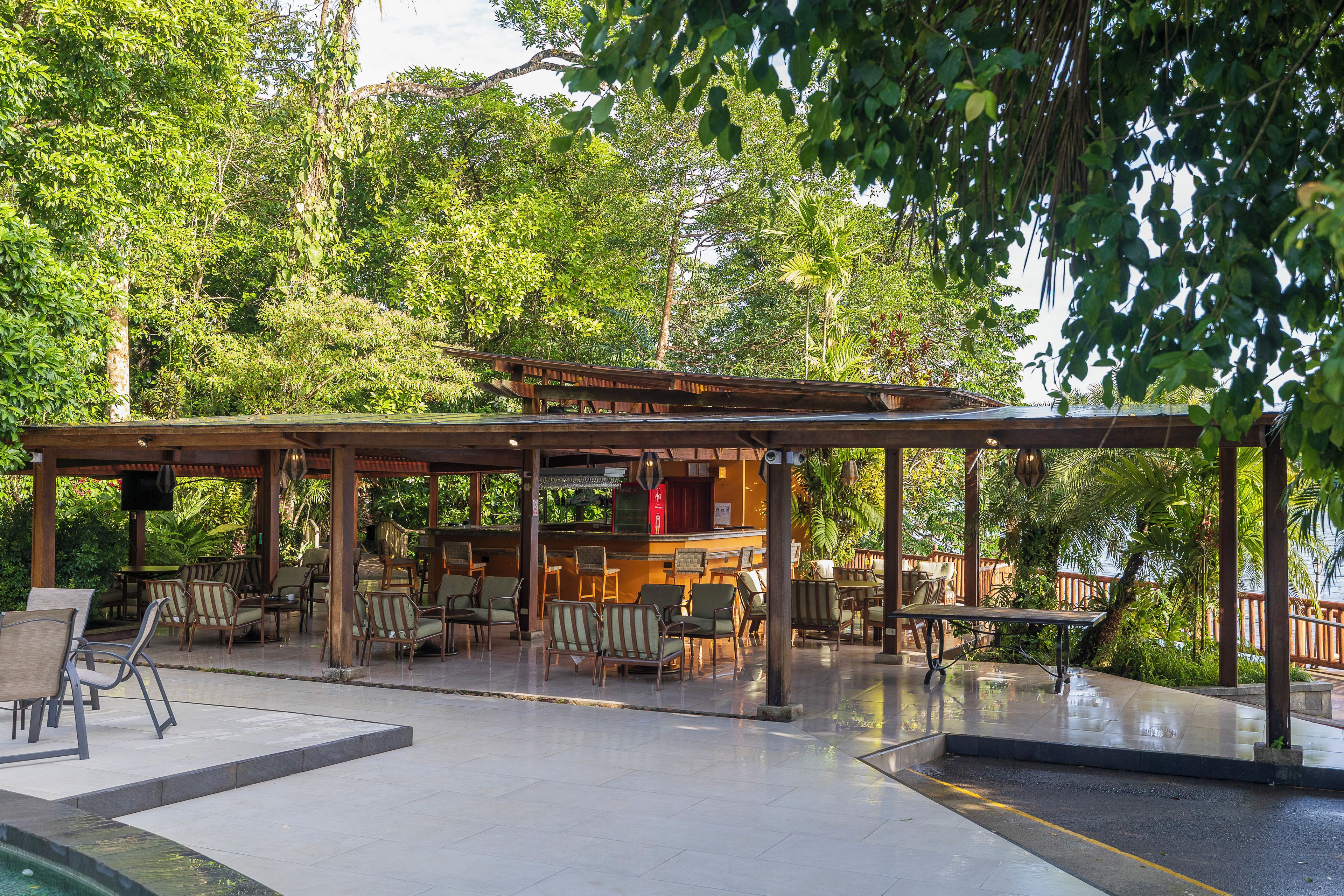 An outdoor patio area with a covered seating area, tables, and chairs.