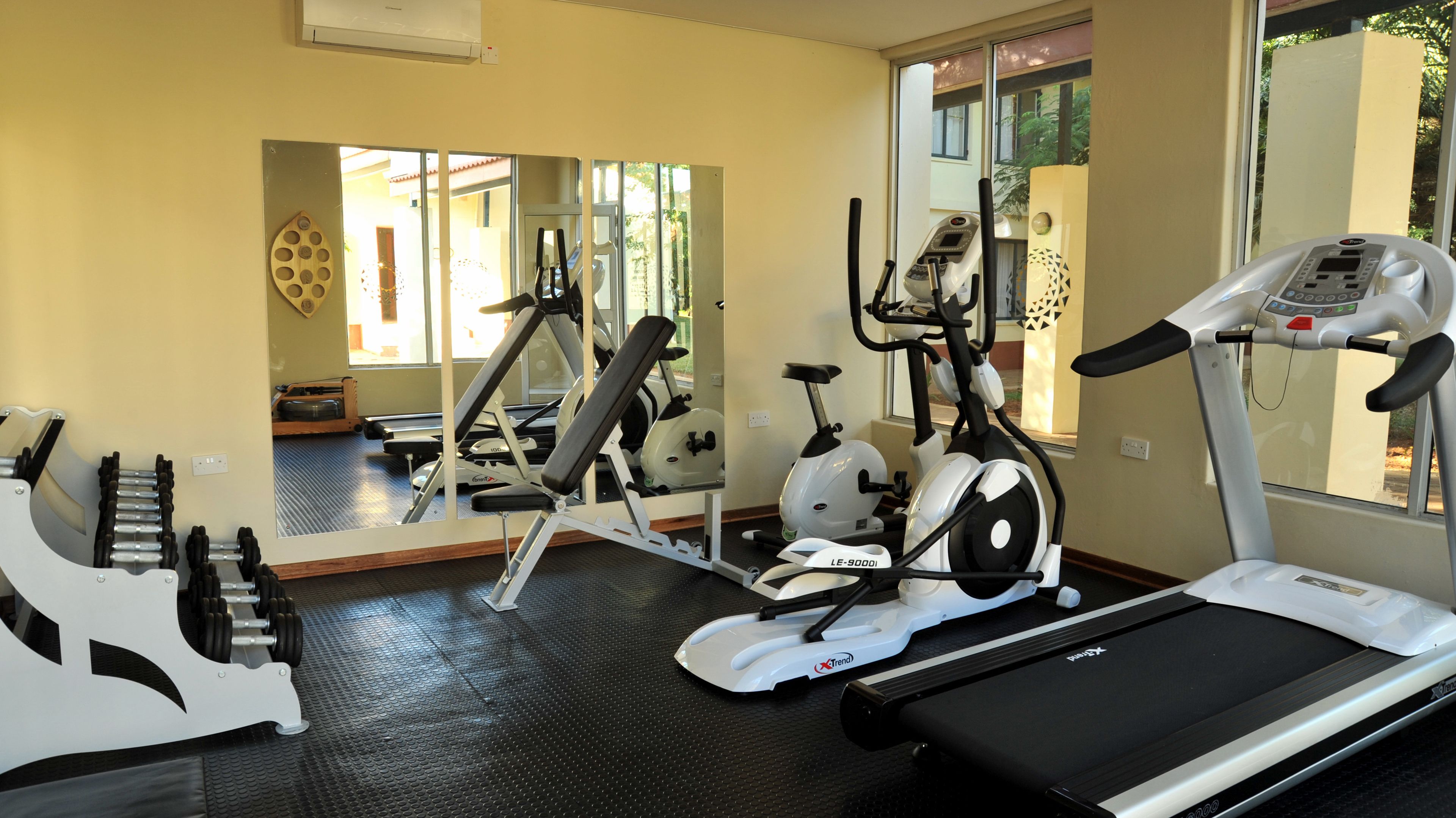Ein Fitnessraum mit Laufbändern, Crosstrainern und einer Gewichtbank.