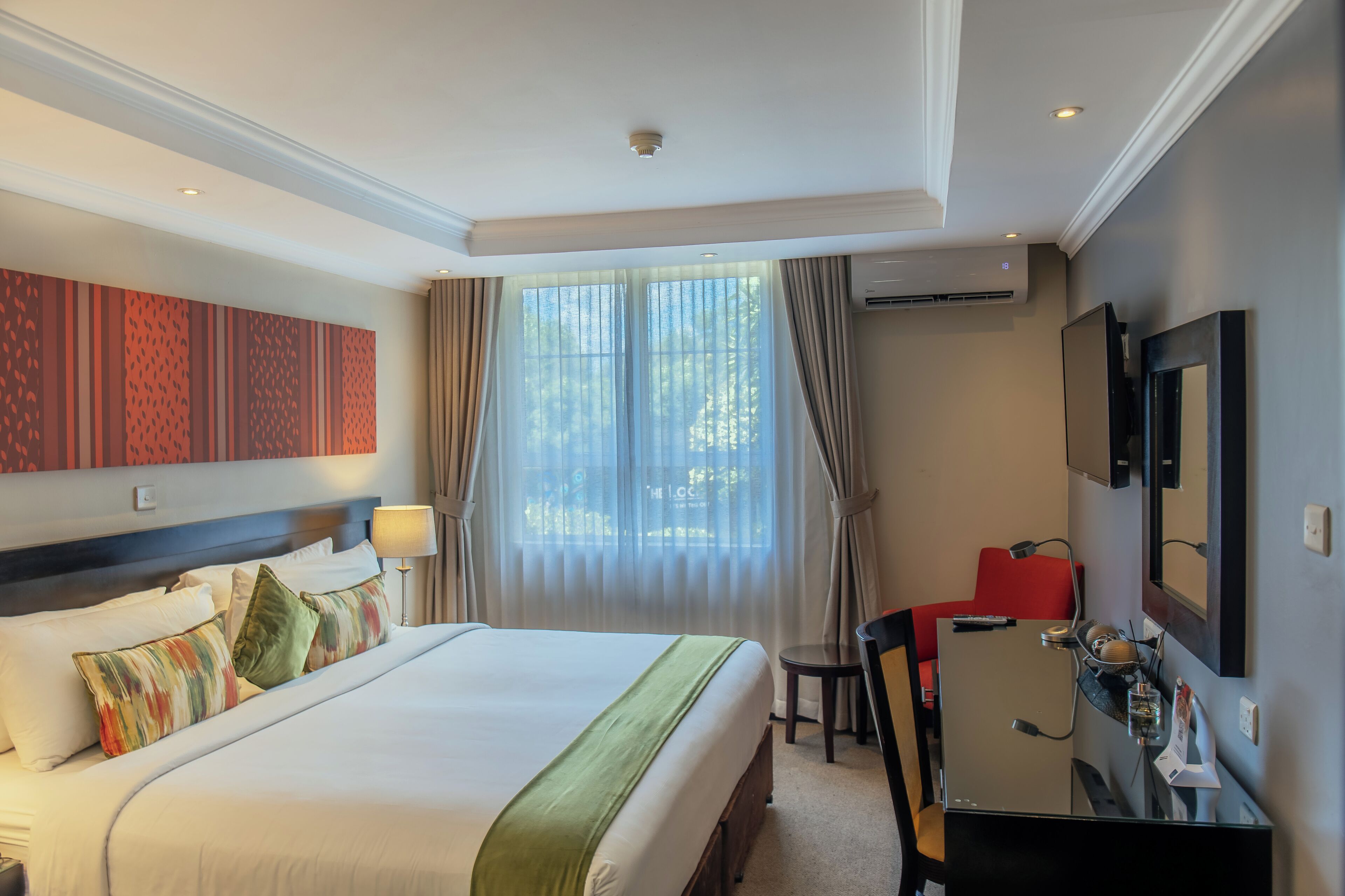 Una habitación de hotel con una cama grande, un escritorio, una silla y un televisor.