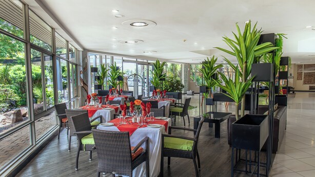 A spacious dining area with high ceilings, large windows, and modern furnishings. - Cresta Lodge Gaborone (Gaborone)