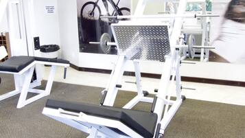 Un gimnasio con equipo de ejercicio, un espejo y un cartel de un ciclista.