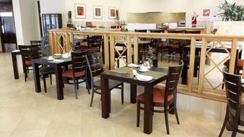 Un restaurant doté de nombreuses tables et chaises, d’un comptoir et d’une grande fenêtre.