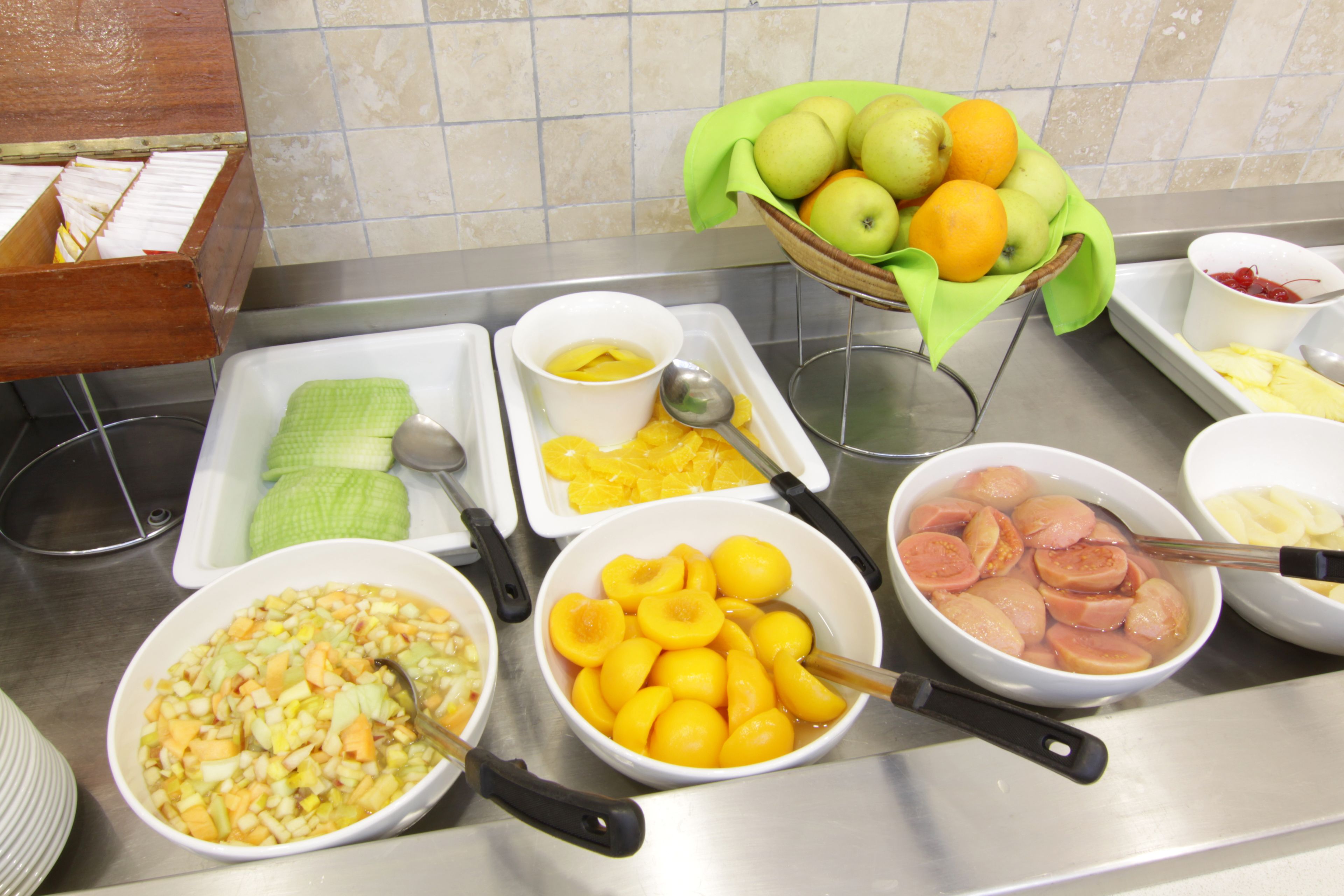 A buffet table with various food items including fruits, vegetables, and sliced meats.