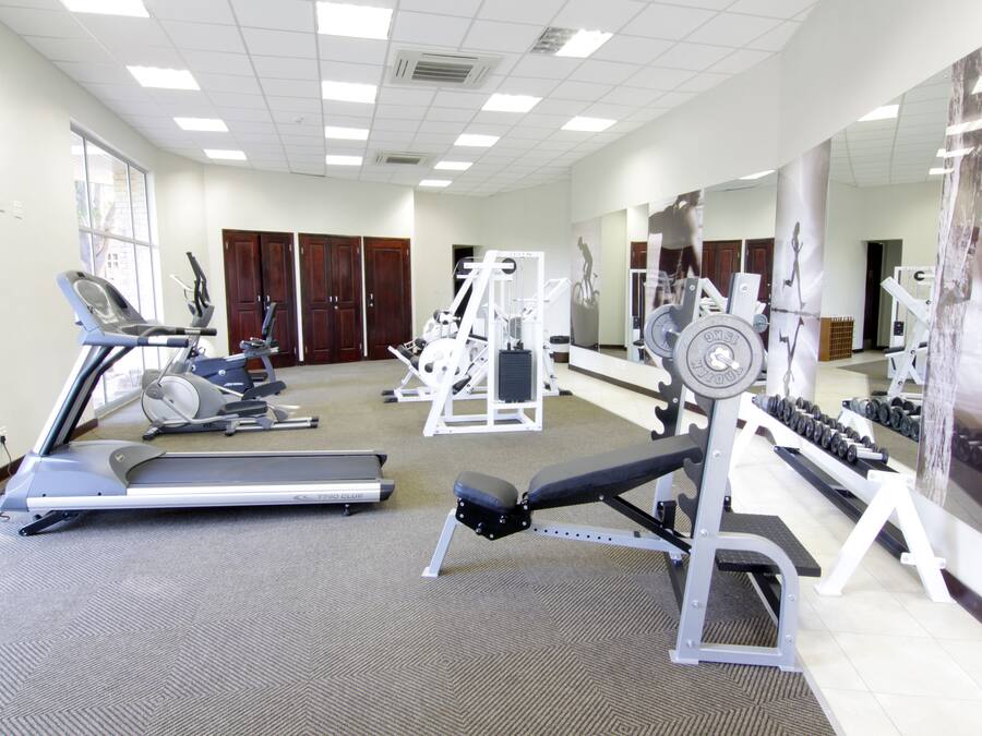 Un gimnasio con cintas de correr, máquinas de pesas y mancuernas.