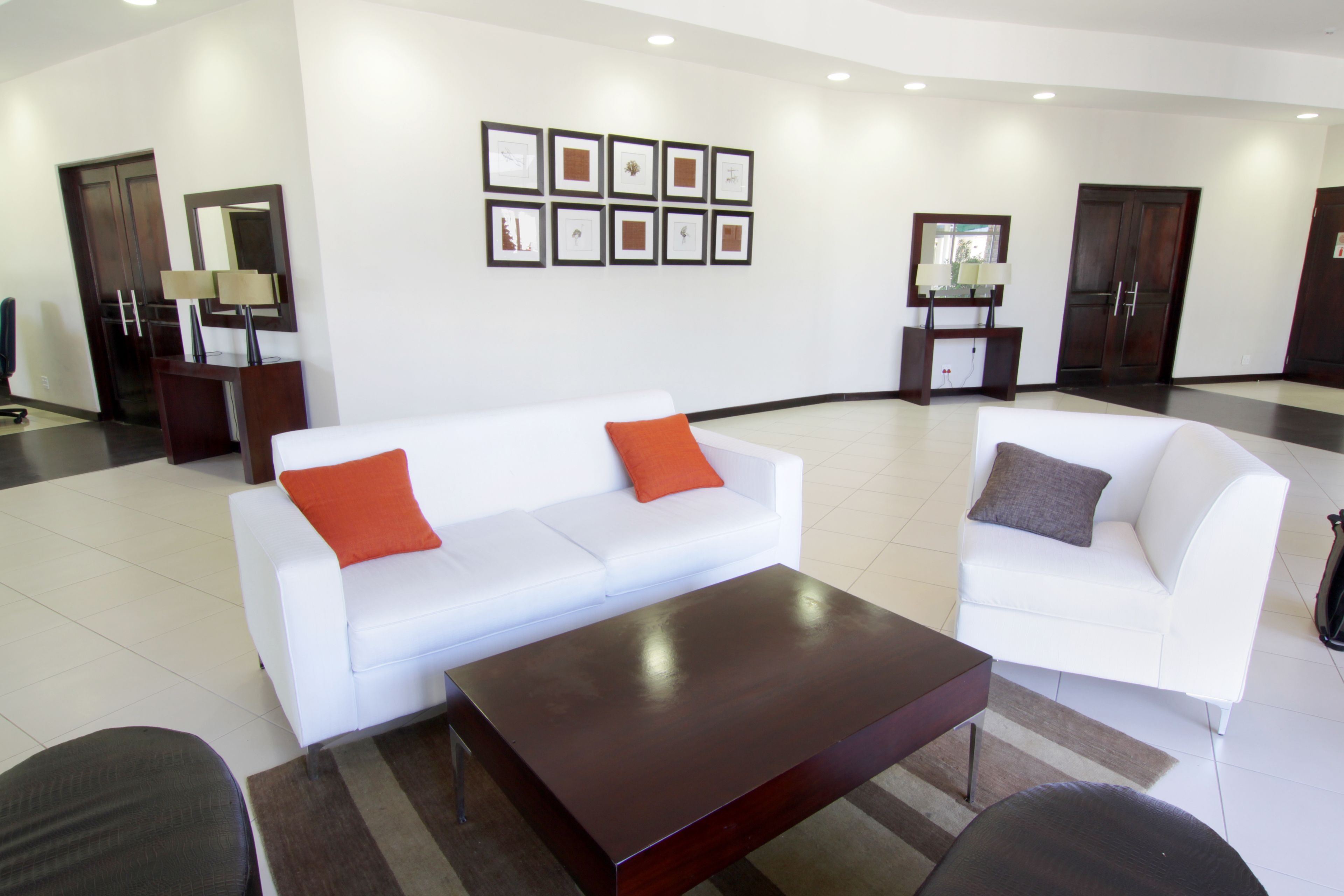 A spacious lobby with two white sofas, a dark wooden coffee table, and framed artwork on the wall.