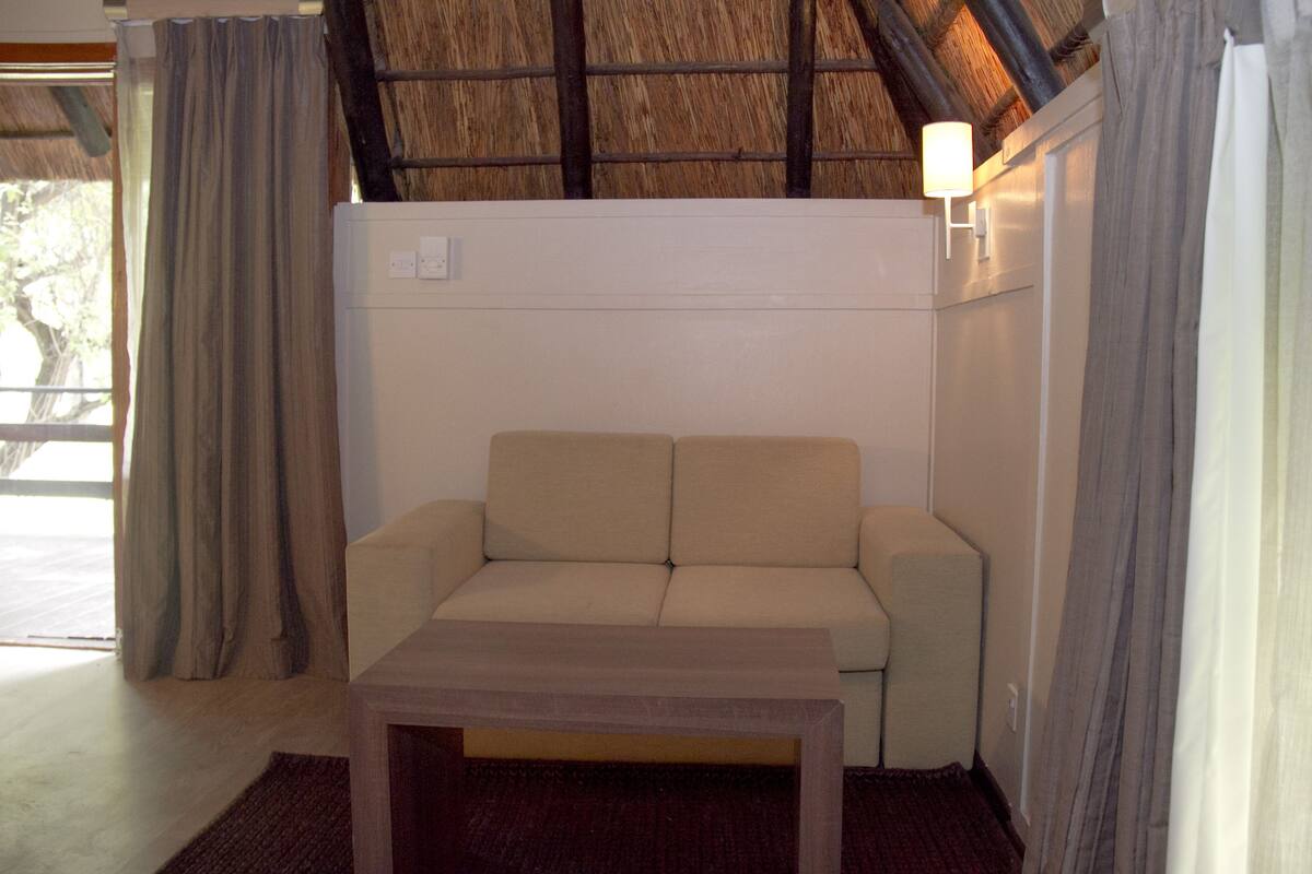 Ein Zimmer mit einer Couch, einem kleinen Tisch und einer Lampe.