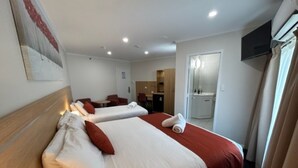 A hotel room with two beds, a TV, and a bathroom visible through an open door. - Adelaide Royal Coach (Kent Town)