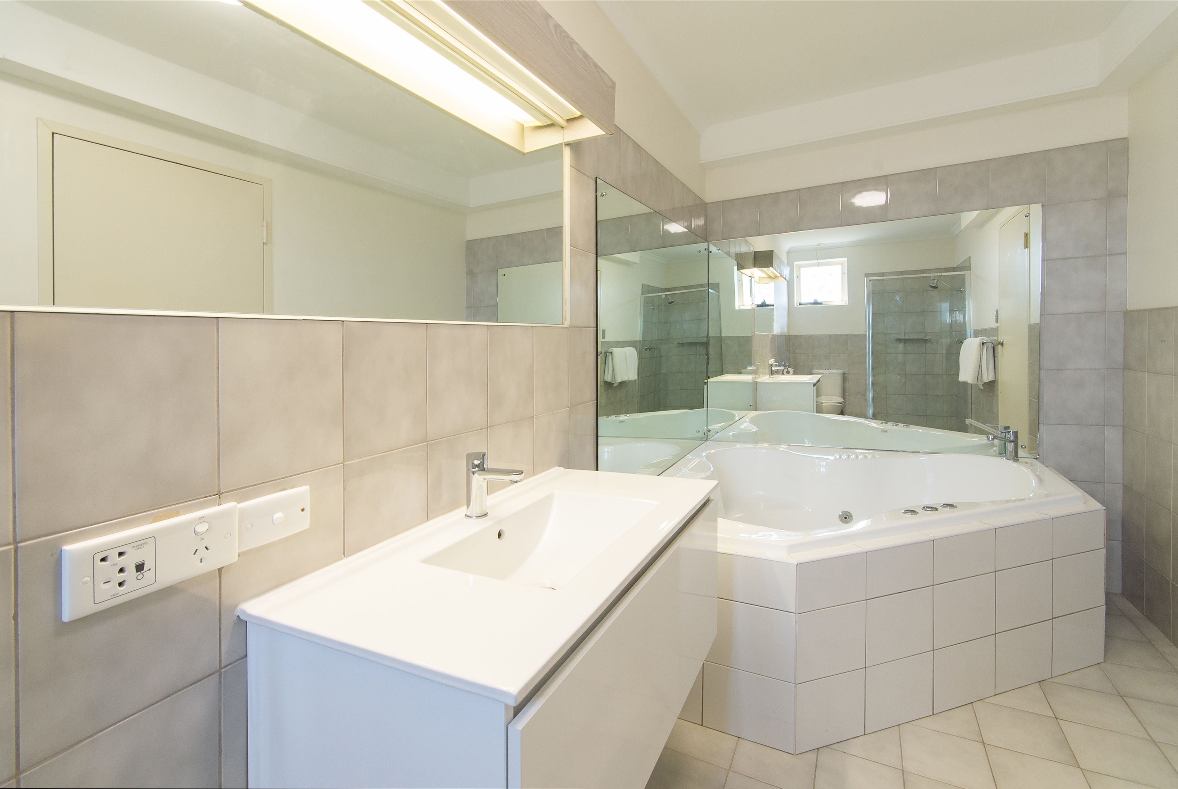 Een moderne badkamer met een groot bad, een aparte wastafel en een douchecabine met glazen wanden.
