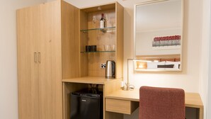 A compact kitchenette with a refrigerator, a coffee maker, and glass shelves. - Adelaide Royal Coach (Kent Town)