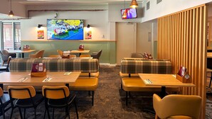 A restaurant with booths and tables, a TV mounted on the wall, and a wooden partition. - Adelaide Royal Coach (Kent Town)