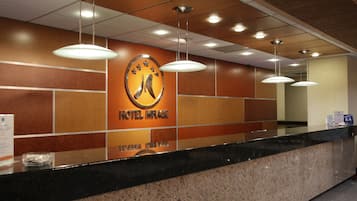Una recepción de hotel con un logotipo, un mostrador y luces colgantes.