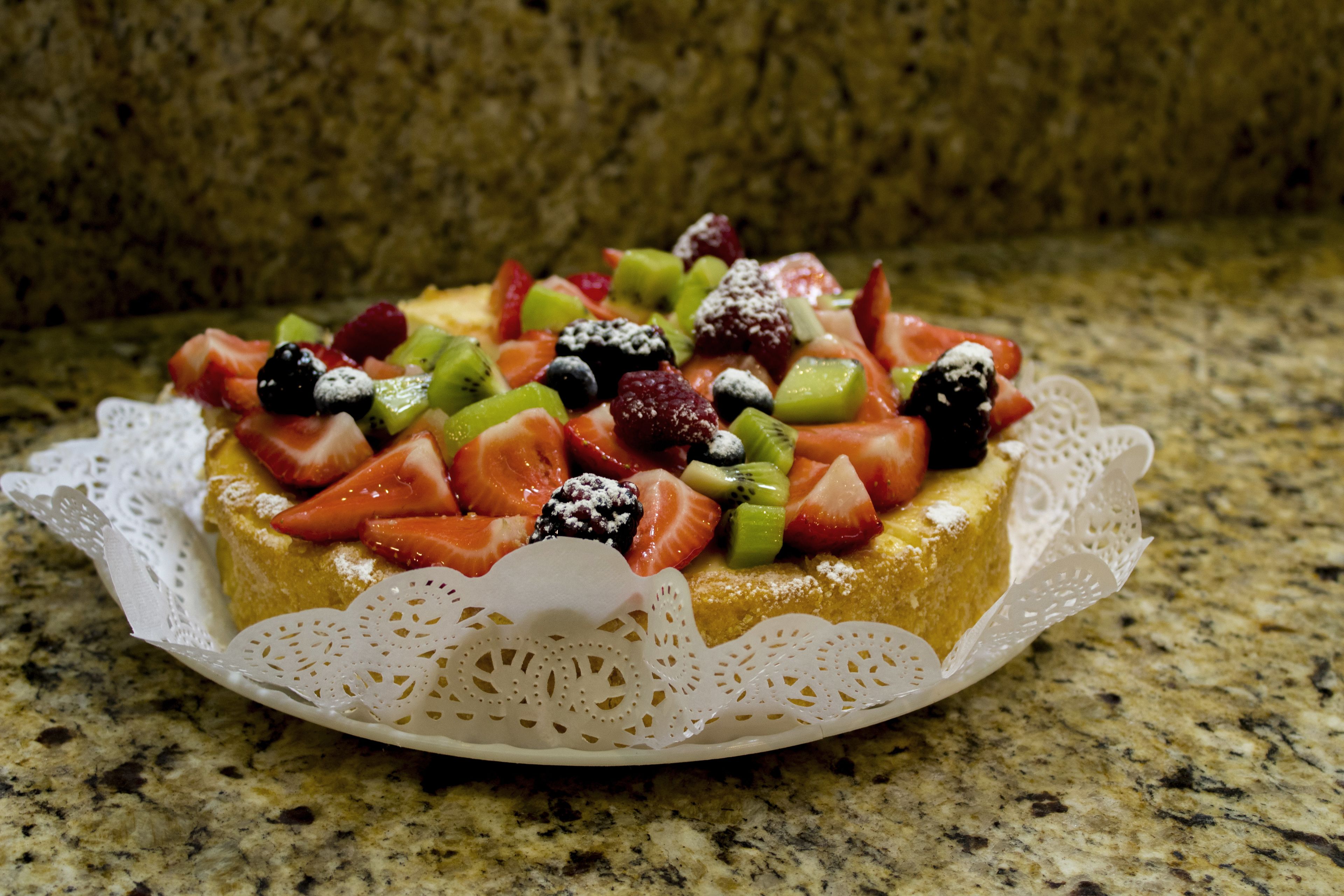 A fruit-topped cake on a lace doily.