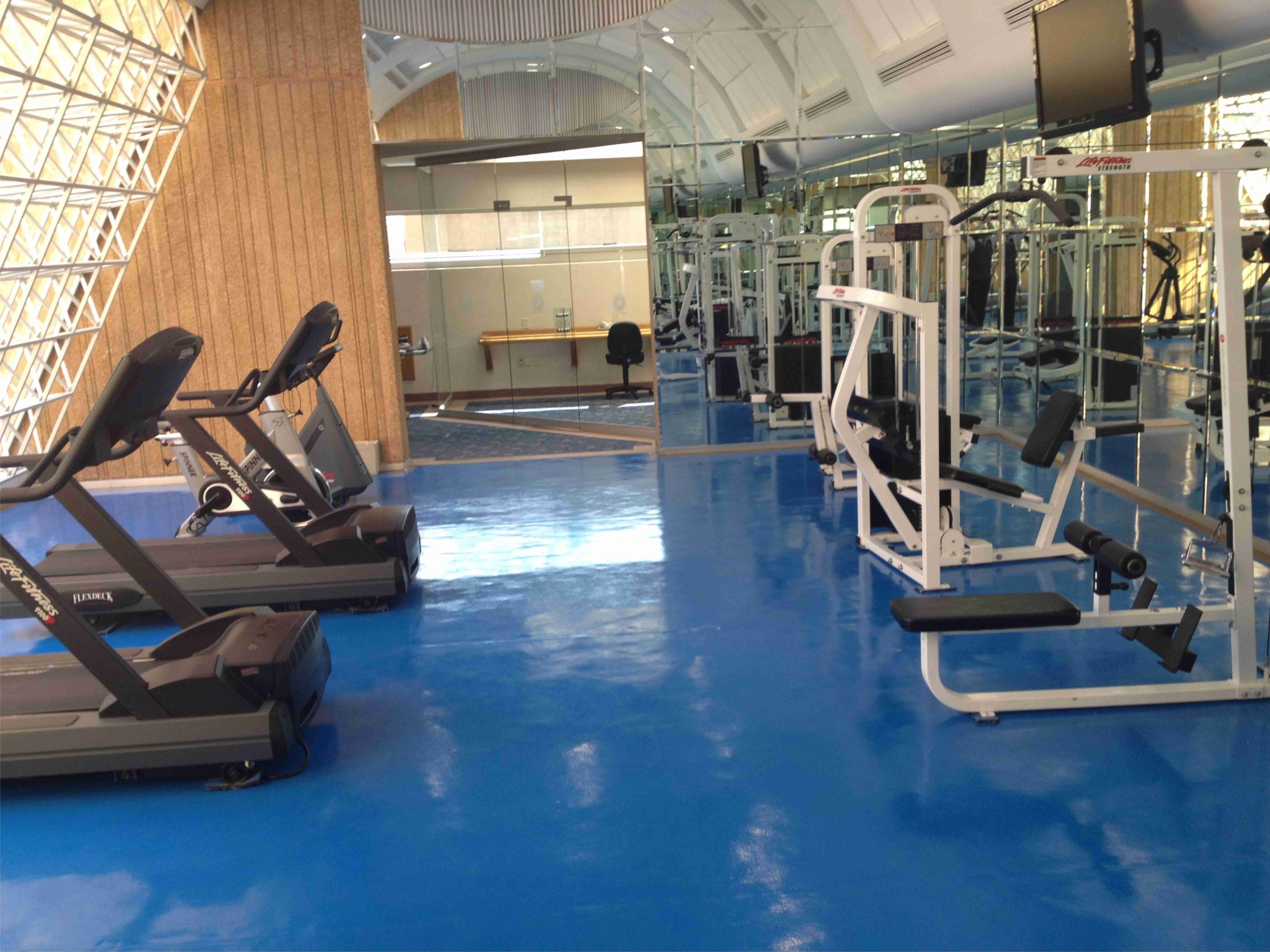 Academia com esteiras e máquinas de musculação.
