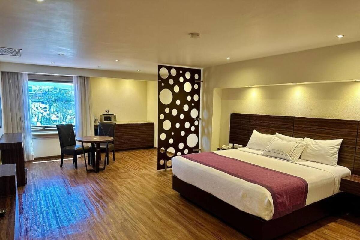 Habitación de hotel con una cama grande, un escritorio y una silla. Hay una ventana con vista a la ciudad.
