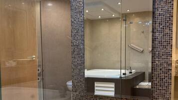 Un baño moderno con cabina de ducha de vidrio, un espejo grande y un salpicadero de azulejos.