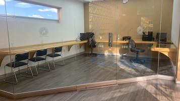 A modern conference room with glass walls, a wooden desk, and two chairs.