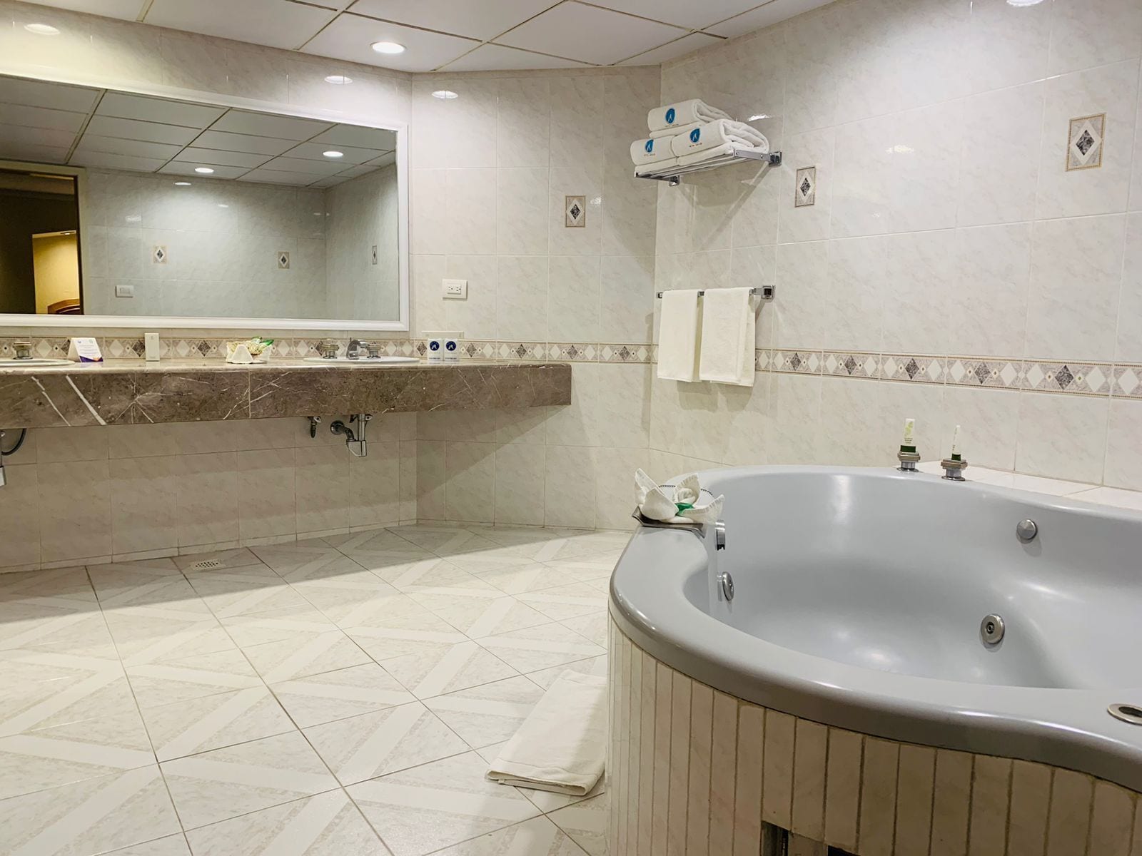A modern bathroom with a large bathtub, a sink with a mirror, and tiled walls.