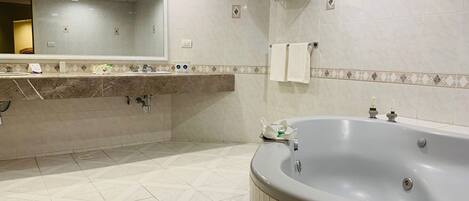 A modern bathroom with a large bathtub, a sink with a mirror, and tiled walls.