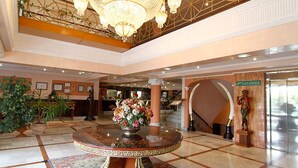 A lobby with a central round table, a chandelier, and a statue. - Begoña Park (Gijon)