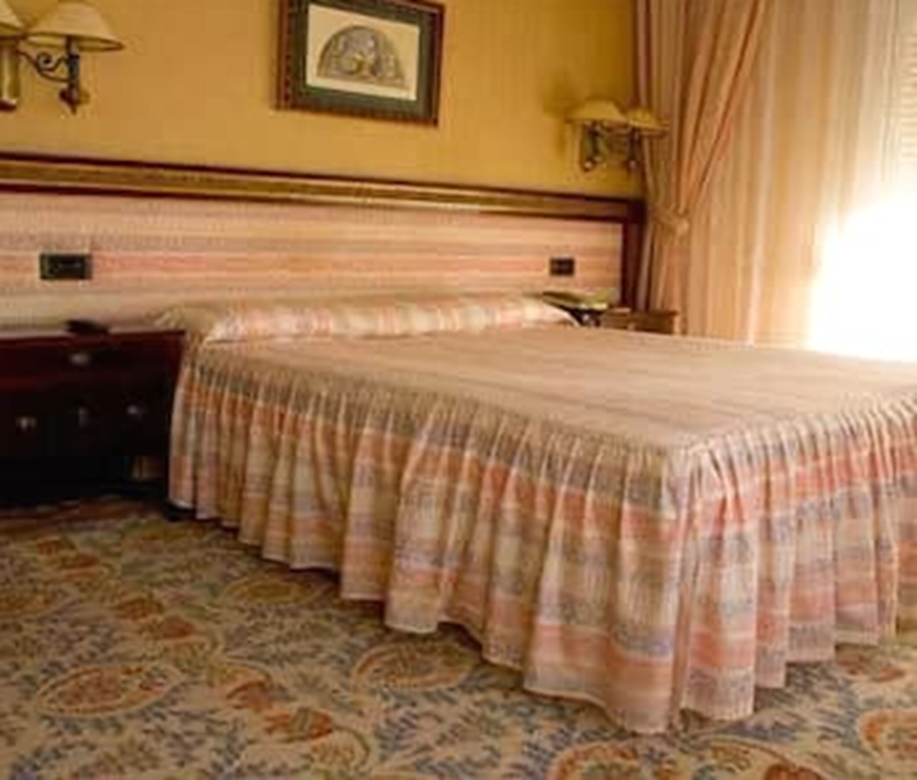 Une chambre d’hôtel avec un grand lit, une table de chevet, une lampe et un tableau encadré au mur.