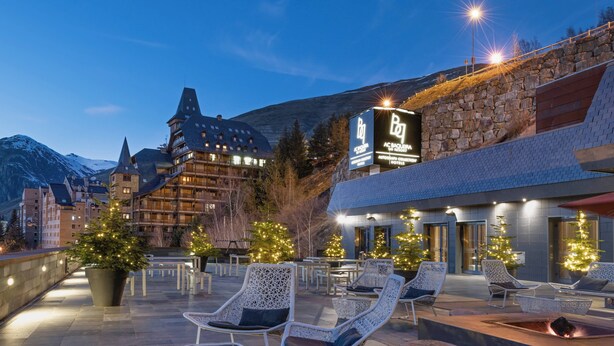 Un hôtel doté d’une terrasse, d’une façade en pierre et de sapins de Noël.