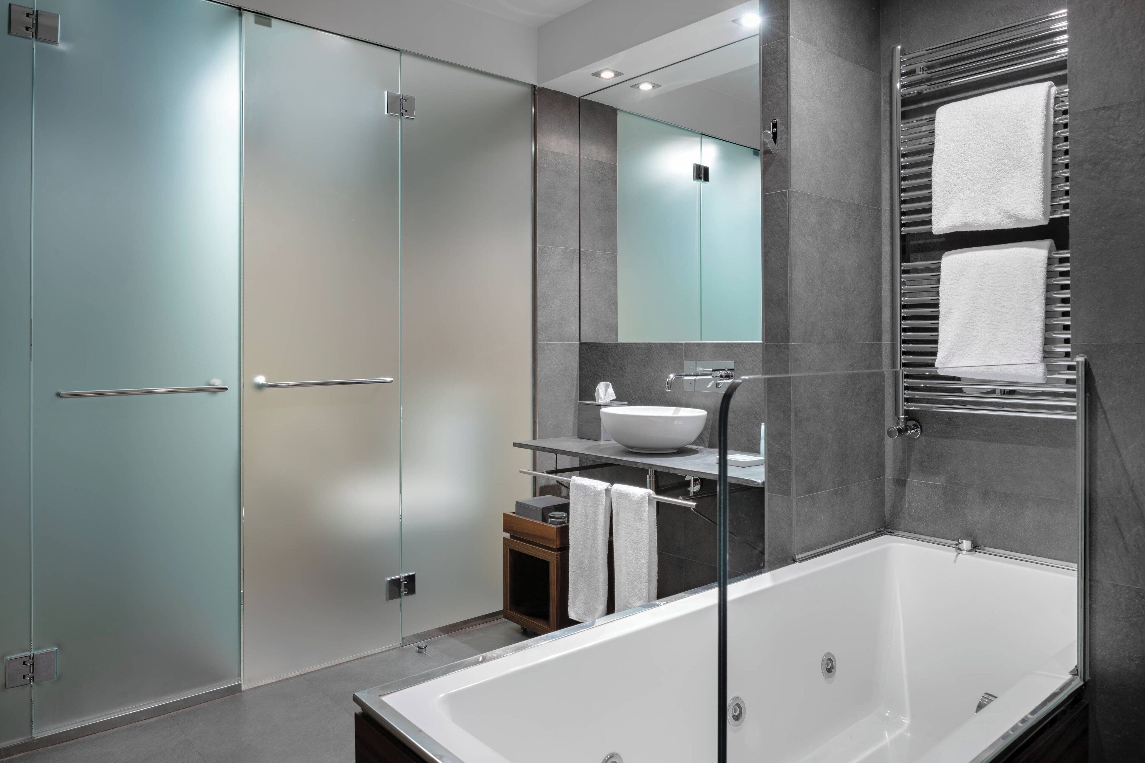 Un bany modern amb una cabina de dutxa de vidre, una banyera independent, un lavabo i un mirall sobre el lavabo.