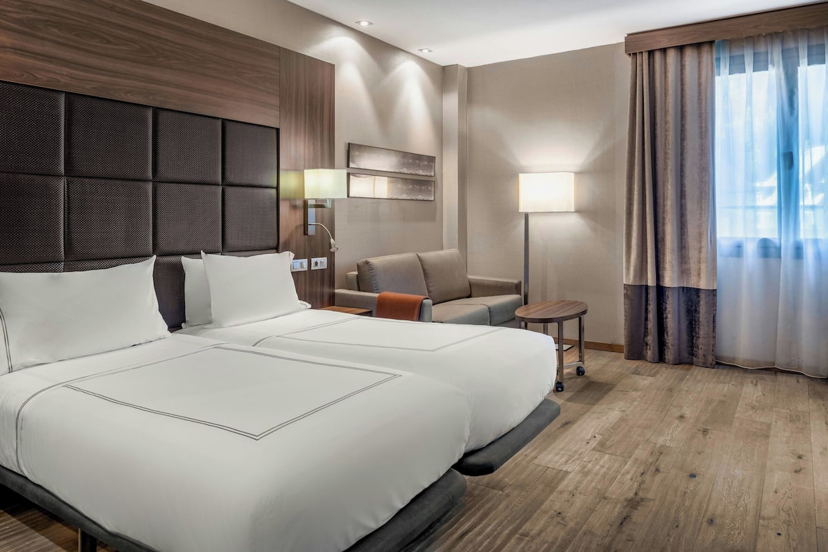 Ein Hotelzimmer mit einem großen Bett, einer Couch, einem kleinen Tisch und einer Lampe.
