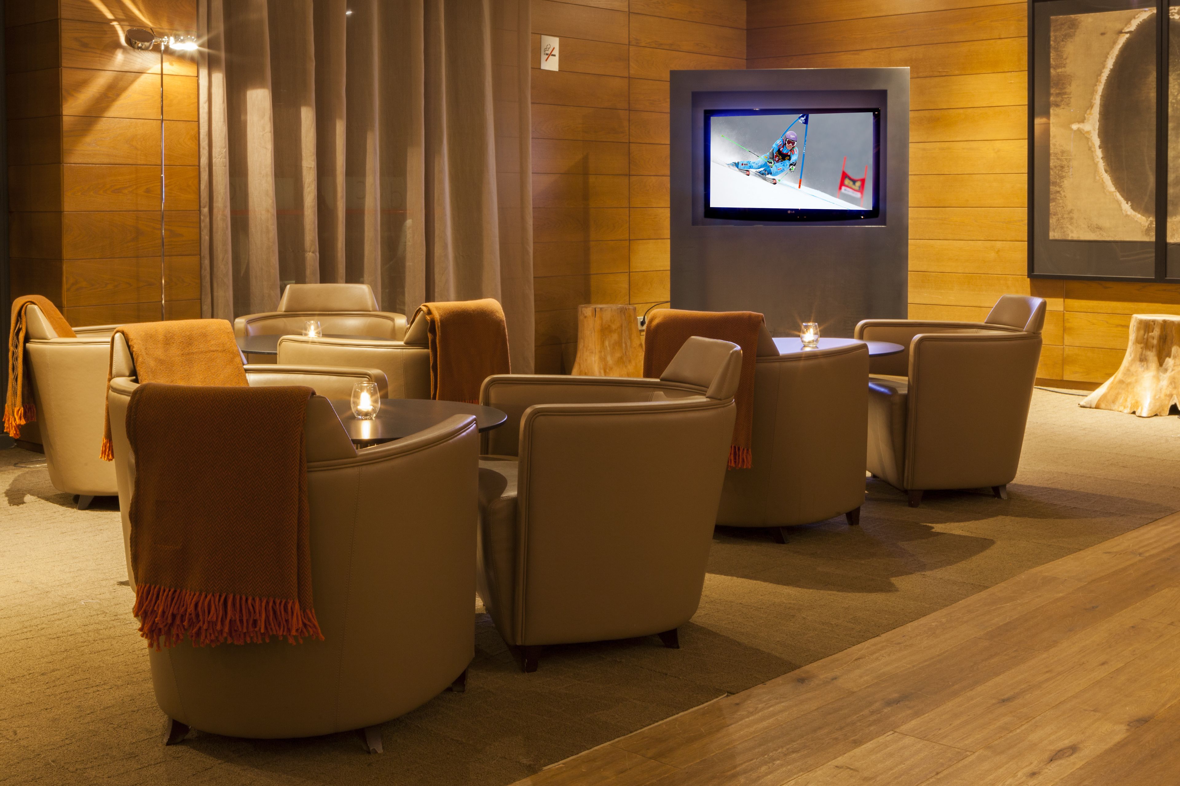 A modern lounge area with leather sofas, a flat-screen TV, and a wooden floor.
