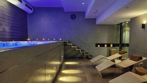 Un espace spa moderne doté d’une piscine chauffée, d’un escalier et de plusieurs coins salon.