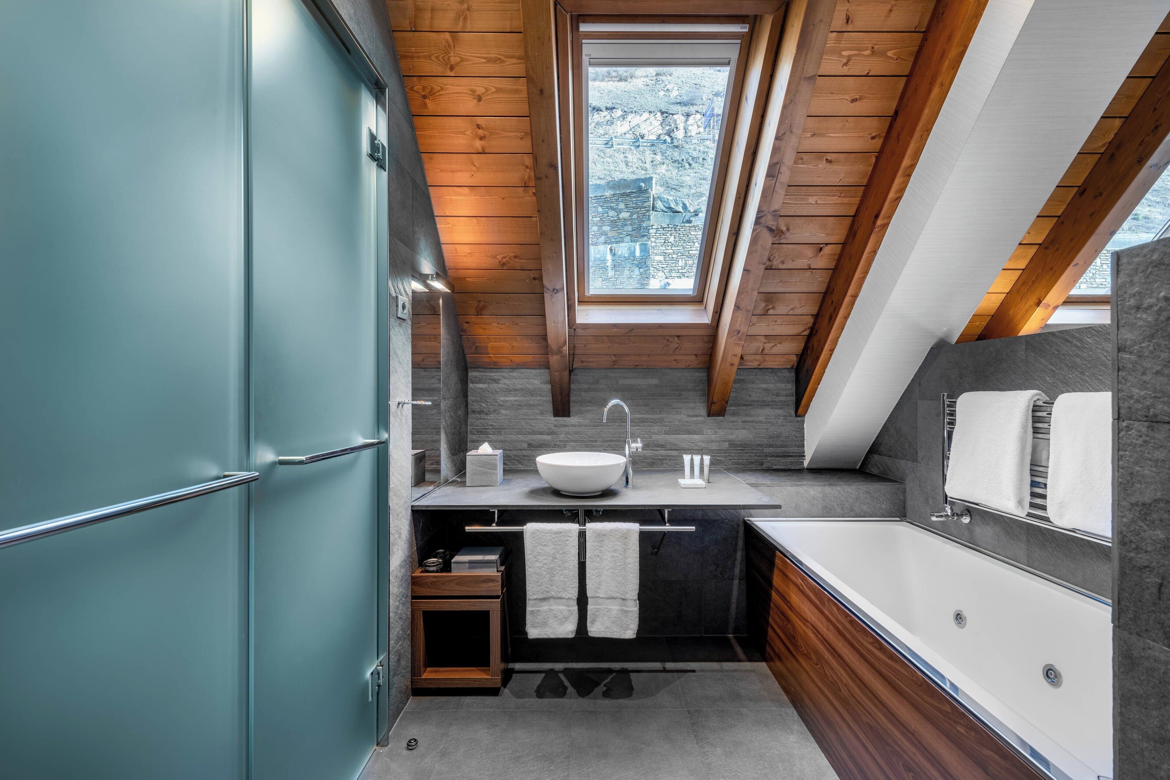 A compact bathroom with a skylight, a freestanding bathtub, and a modern sink.