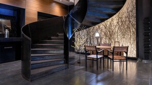Un intérieur moderne avec un escalier en colimaçon, des murs lambrissés et un coin repas comprenant des chaises et une table.