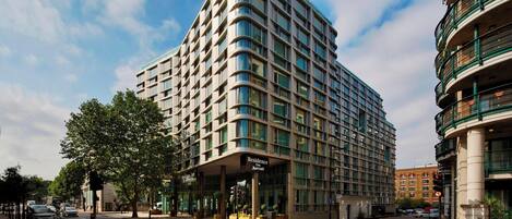A modern hotel with a curved facade, large windows, and a prominent entrance.